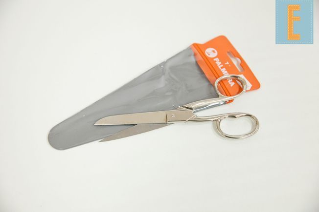 Un par de tijeras plateadas sobre una superficie blanca.