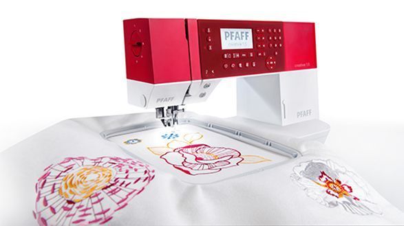 Una máquina de coser roja y blanca está sobre una mesa.
