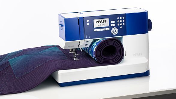 Una máquina de coser azul y blanca está sobre una mesa.