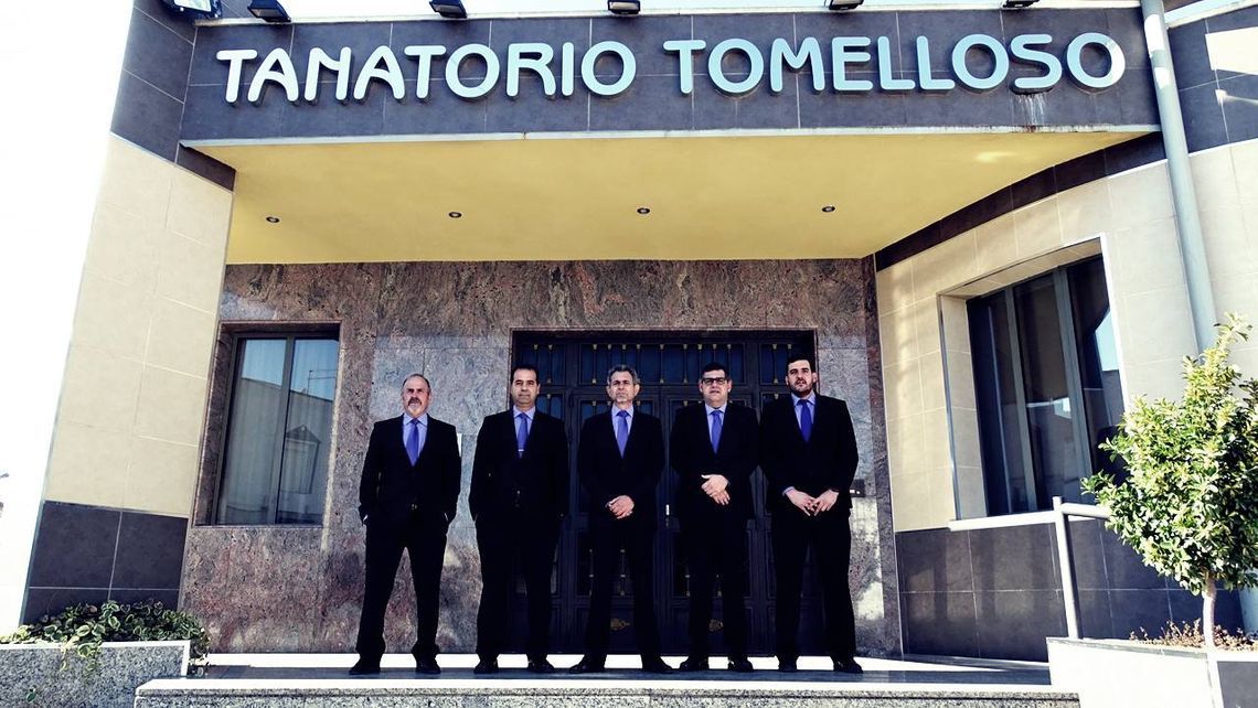 Cinco hombres de traje están de pie frente al edificio