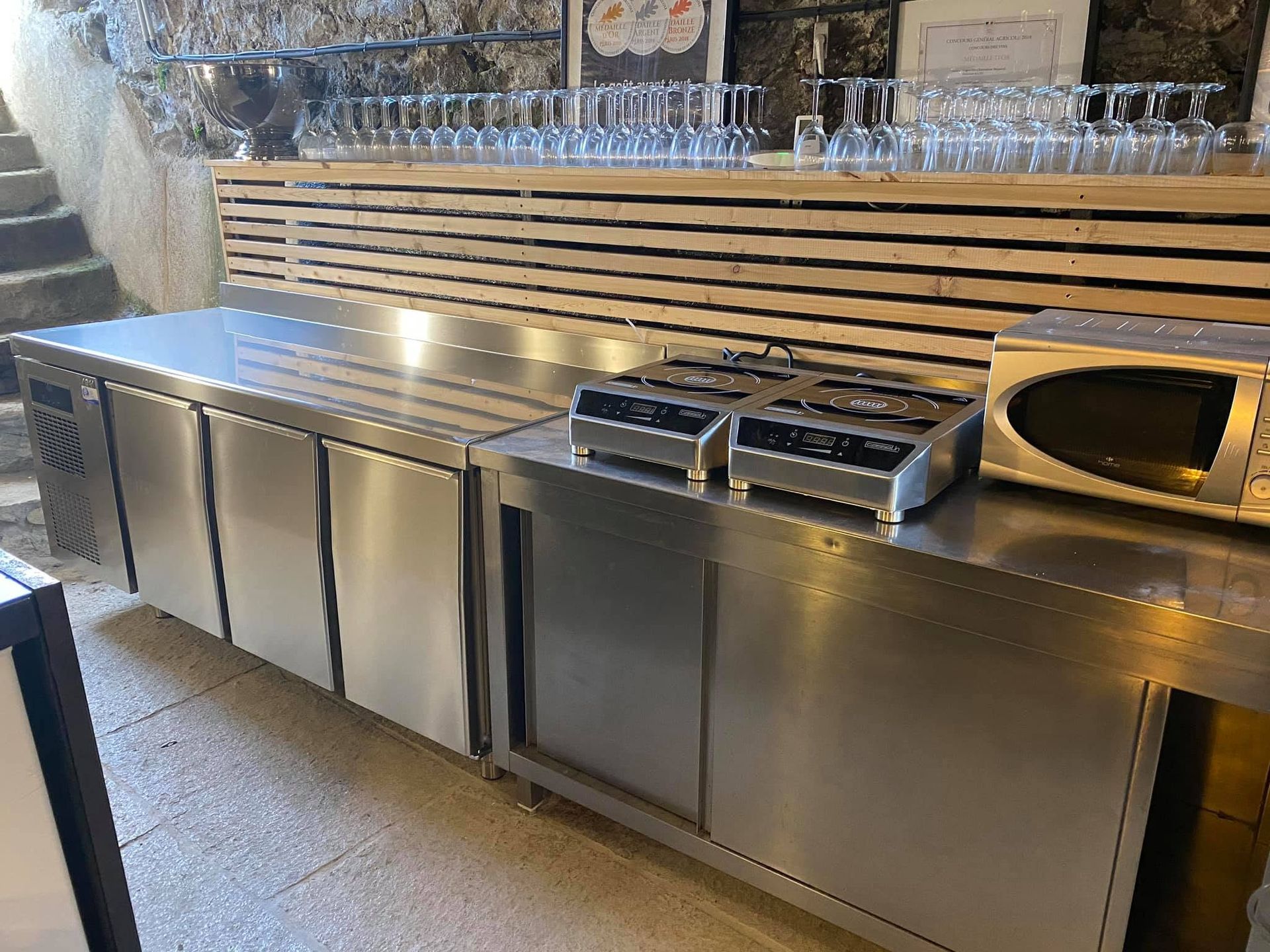 Plan de travail de cuisine en acier inoxydable avec éviers intégrés et placards de rangement.