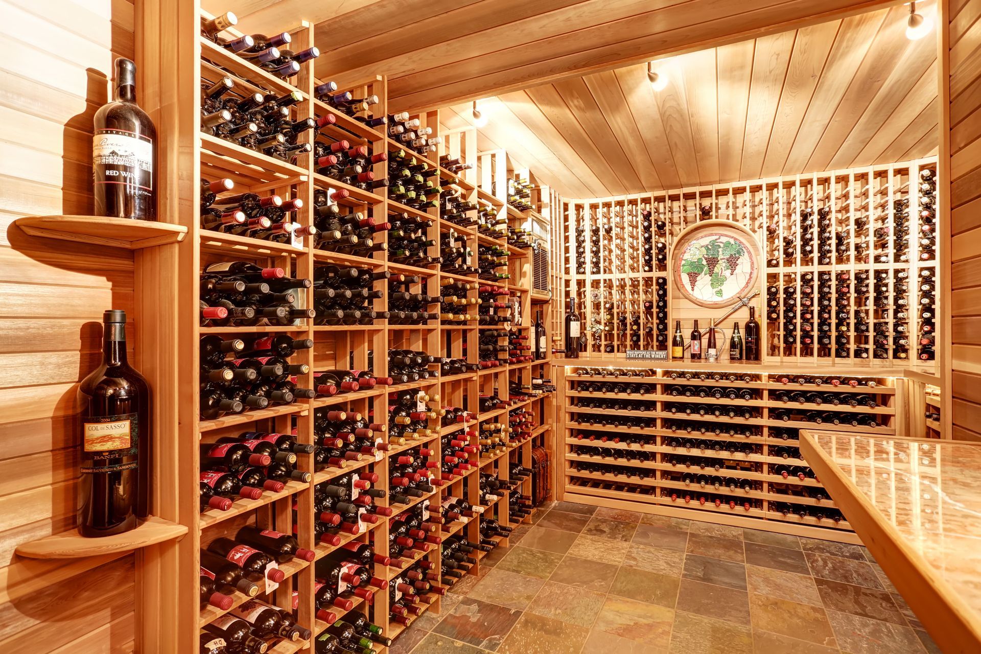 Cave à vin lambrissée avec des rangées de bouteilles de vin sur des étagères et un espace de dégustation.