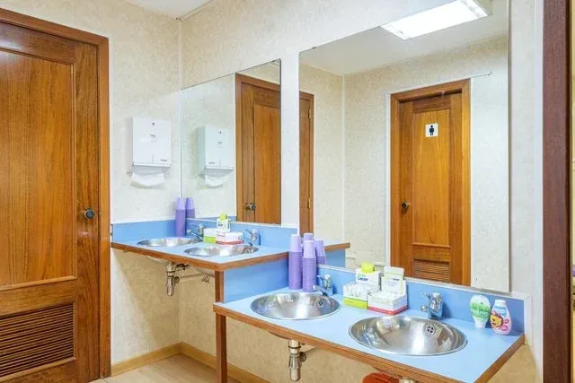 Un mueble de baño con dos lavabos circulares de acero inoxidable, una encimera azul y un gran espejo de pared.