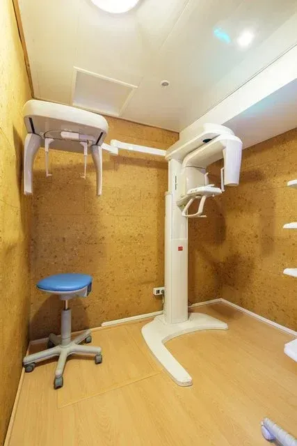 En una pequeña habitación con paredes texturizadas de color beige, suelo de madera clara y un taburete azul con ruedas