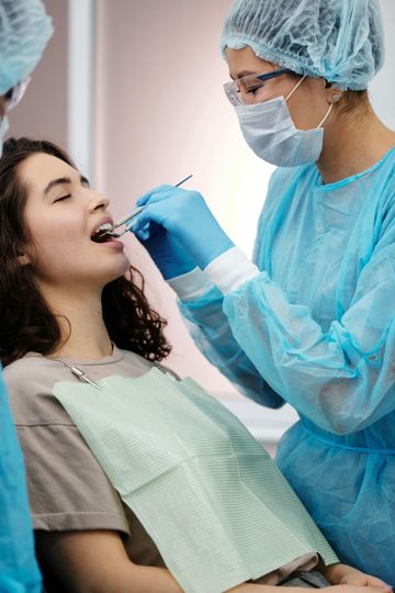 Un dentista con equipo de protección examina a un paciente en el sillón dental, utilizando