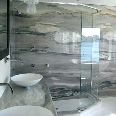 Eine gläserne Dusche an einer mit Stein verkleideten grau braunen Wand