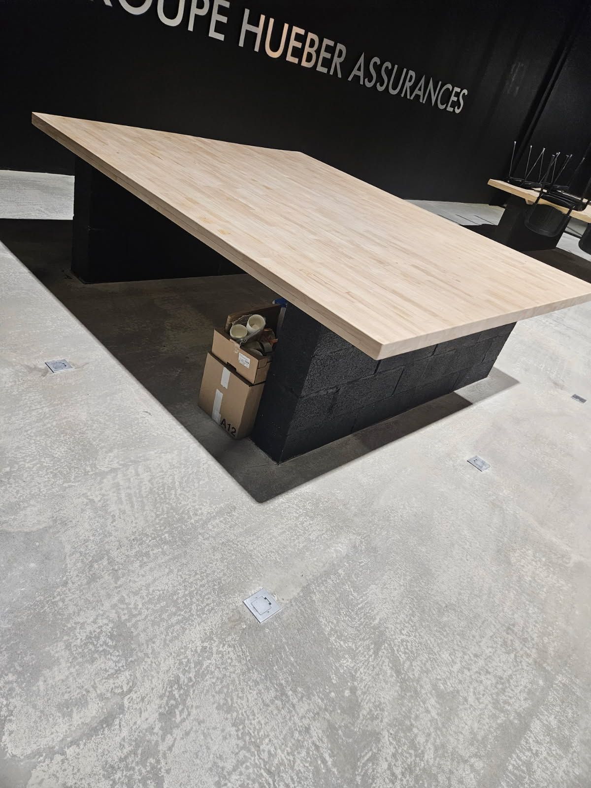 Table de conférence en bois clair avec pied central noir dans un showroom moderne