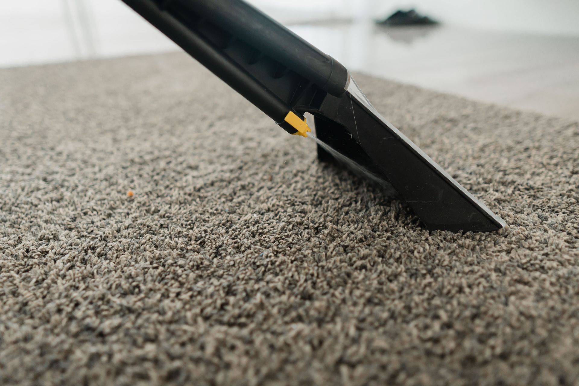 Gros plan d'une buse de nettoyage de tapis extrayant la saleté d'un tapis beige
