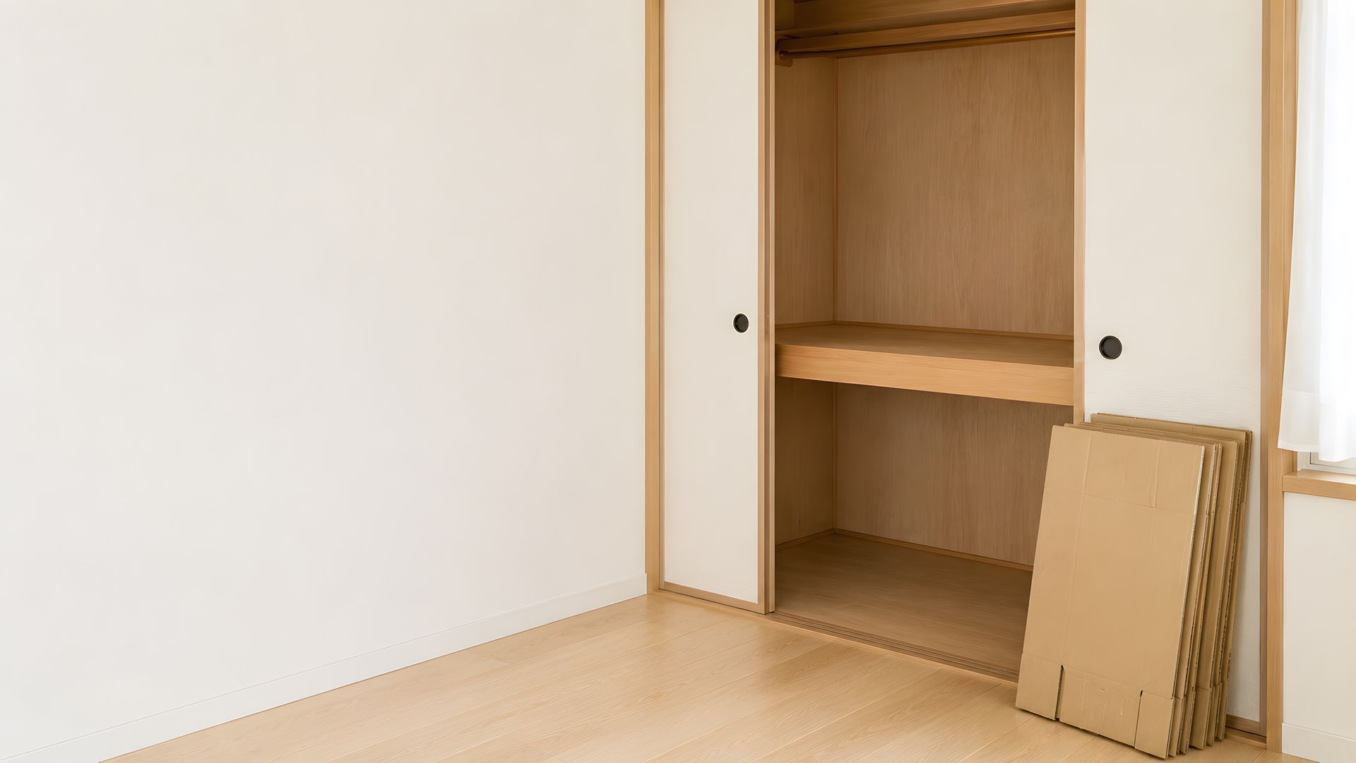 Placard en bois ouvert avec portes coulissantes blanches dans une pièce épurée aux tons clairs