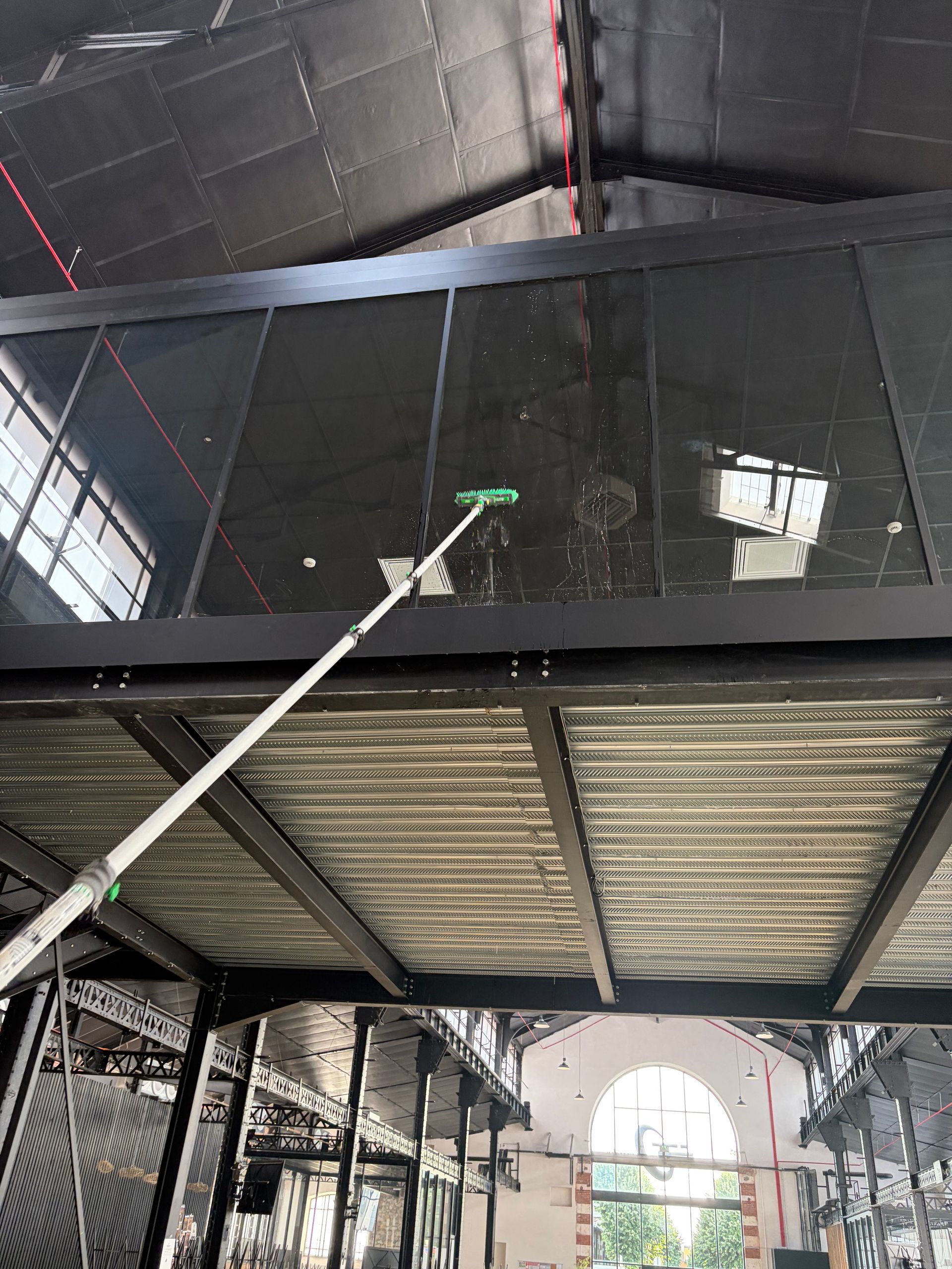 Deux laveurs de vitres suspendus à des cordes nettoient un immeuble de bureaux aux façades en verre miroir.