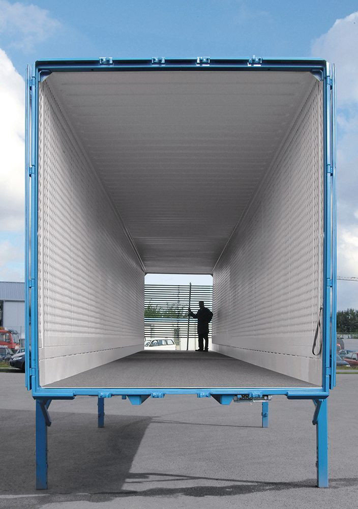 Ein Mann steht auf der Ladefläche eines leeren blauen Lastwagens