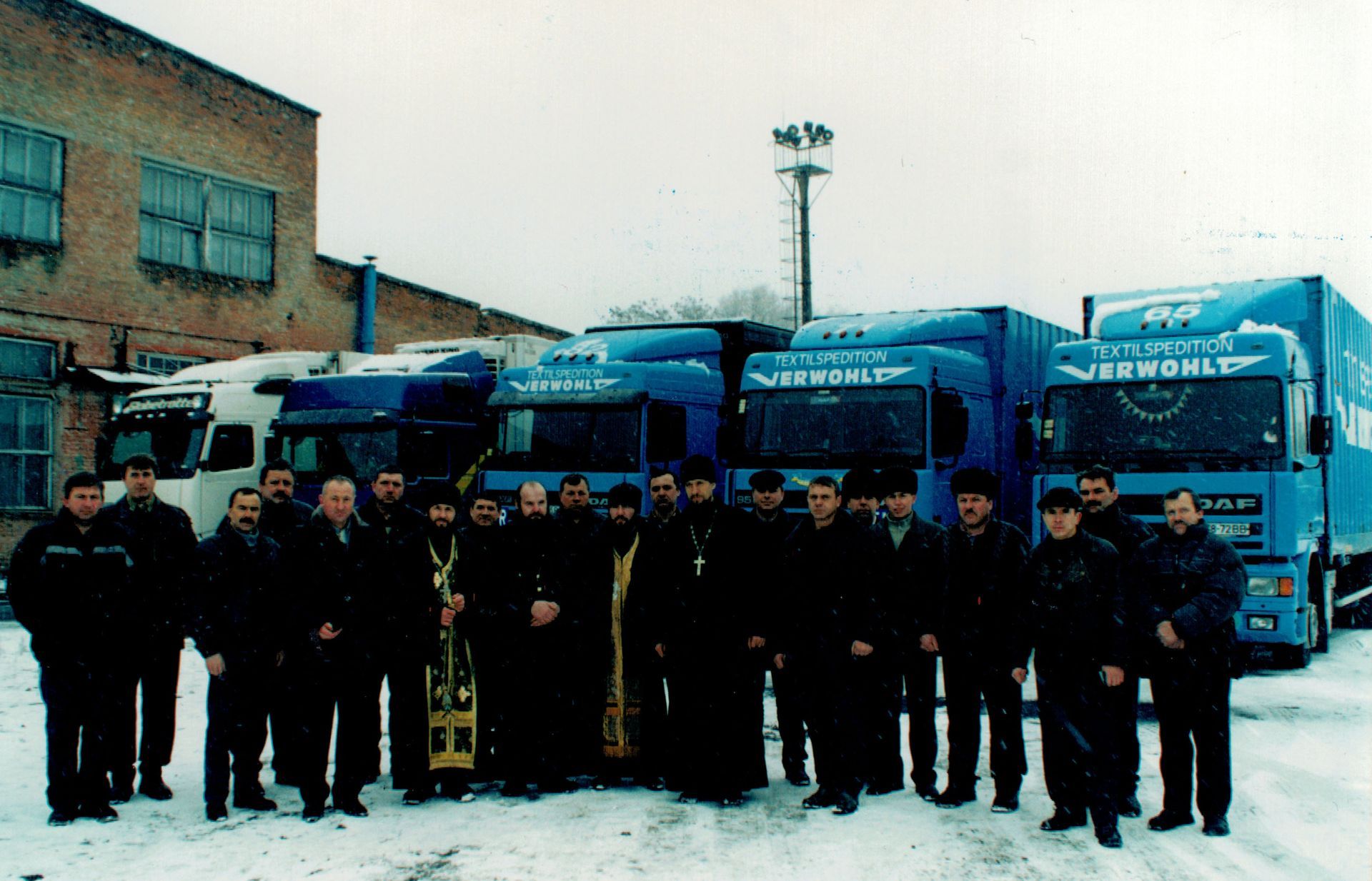 Eine Gruppe von Männern steht vor Lastwagen mit der Aufschrift „Verworld“