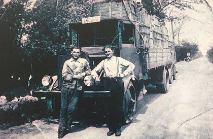 Ein Schwarzweißfoto von zwei Männern, die neben einem Lastwagen stehen