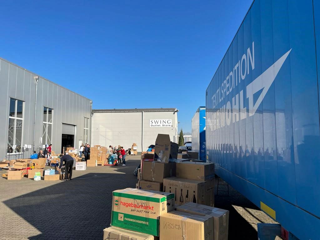 Ein Lagerhaus voller Kisten und einem blauen Lastwagen.