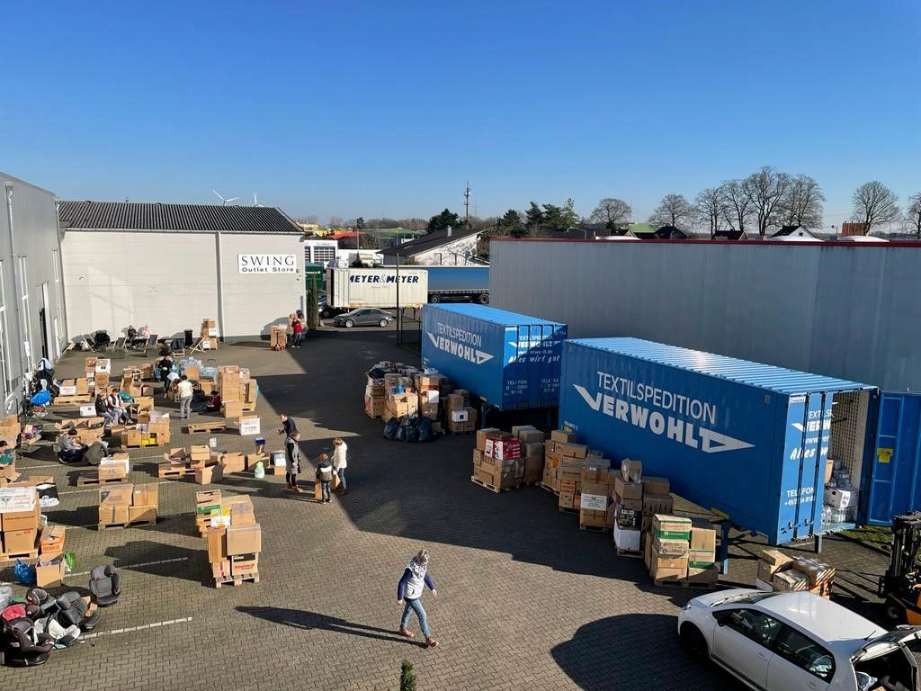 Eine Gruppe von Menschen steht vor einem Stapel von Kisten und Taschen.