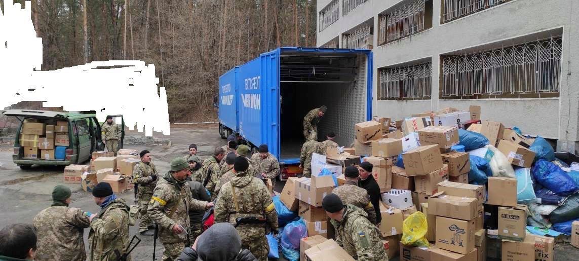 Eine Gruppe Soldaten steht vor einem mit Kisten beladenen Lastwagen.