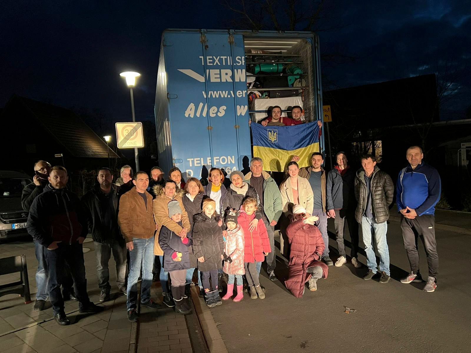 Eine Gruppe von Menschen posiert vor einem Lastwagen für ein Foto.