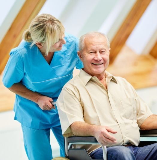 Eine Krankenschwester hilft einem älteren Mann im Rollstuhl