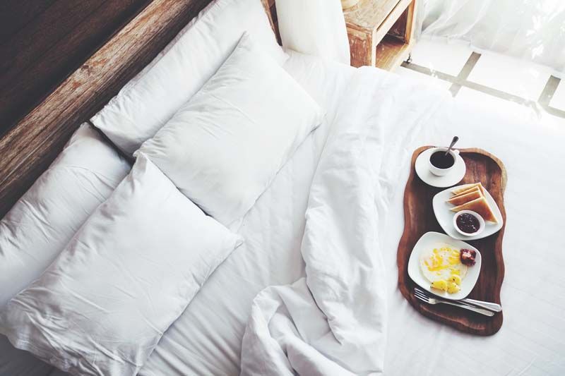 Una cama con una bandeja de comida y café encima.
