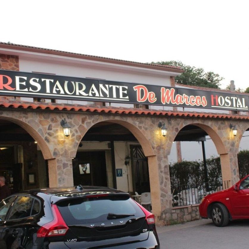 Un coche negro está aparcado delante de un restaurante llamado restaurante de marcos hostal