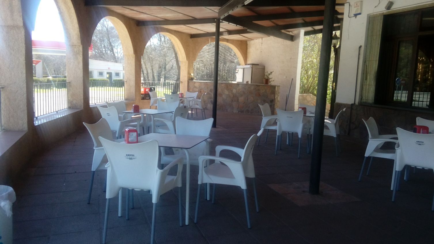 Un patio con mesas y sillas bajo un dosel.