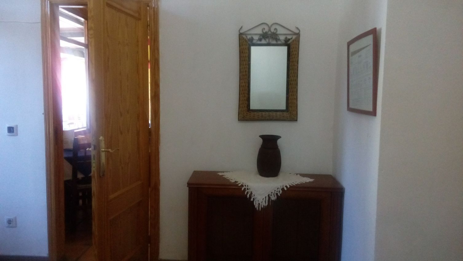 Un pasillo con un espejo y un jarrón sobre una mesa.