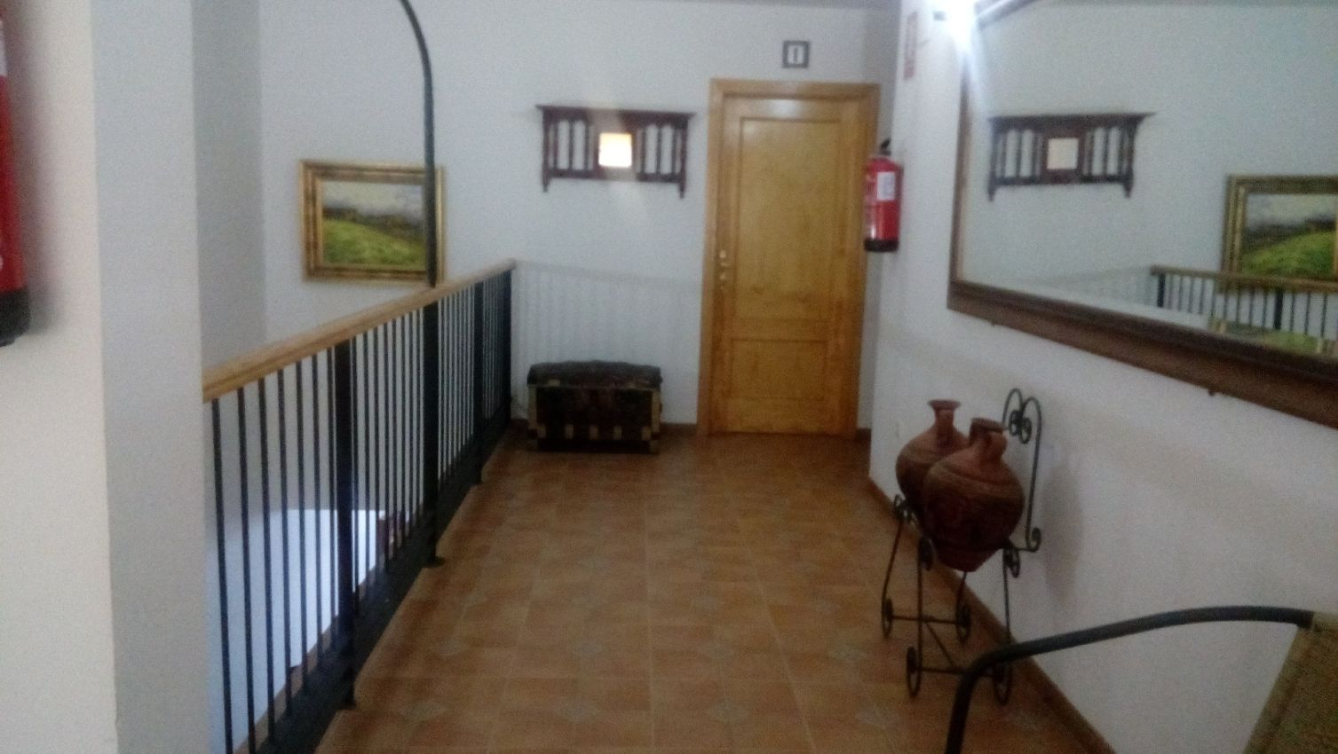 Un pasillo con una silla y un espejo en la pared.