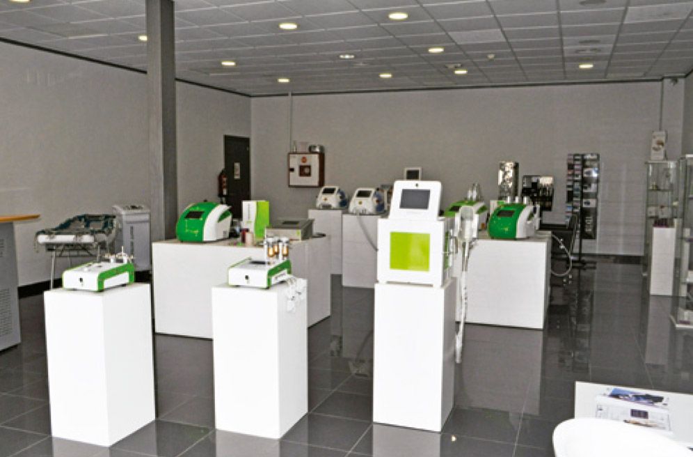 Dentro de una tienda moderna, se exhiben dispositivos médicos de color blanco y verde sobre pedestales blancos.