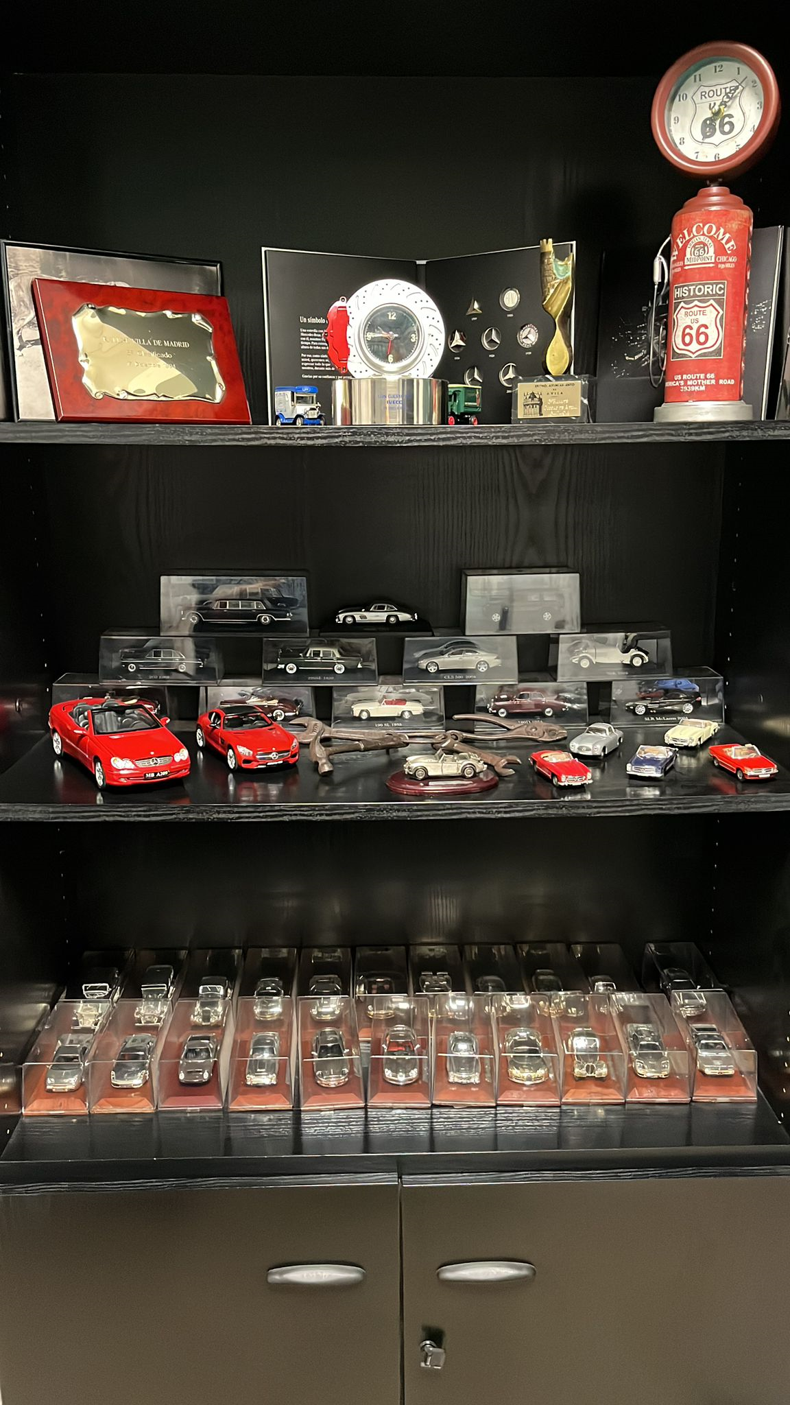 Un estante lleno de muchos coches de juguete y trofeos.