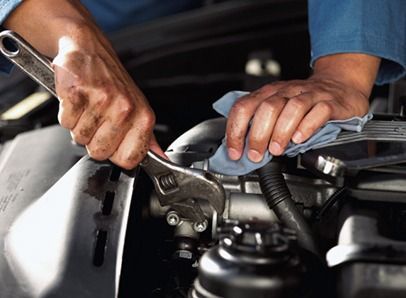 Un hombre está trabajando en el motor de un automóvil con una llave inglesa.
