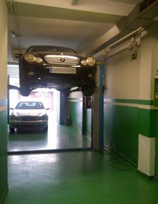 Un Mercedes está en un elevador en un garaje.