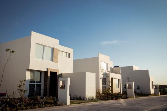 Casas blancas modernas bajo un cielo azul claro.