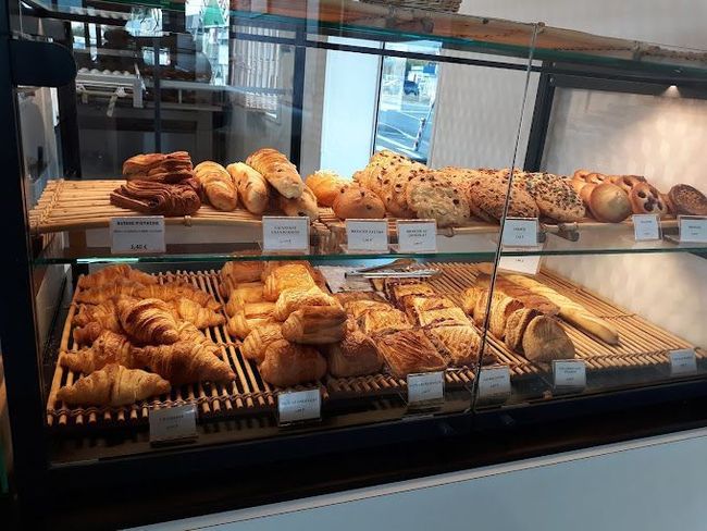 Une vitrine de boulangerie remplie de rangées de croissants dorés, de viennoiseries et de pains artisanaux disposés sur des plateaux.