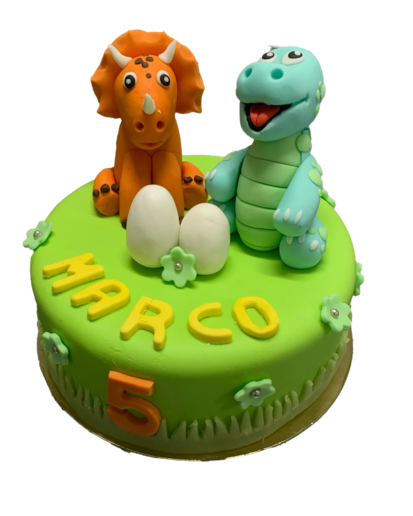 Un gâteau d'anniversaire vert décoré de deux figurines de dinosaures, de deux œufs blancs, du nom MARCO et du chiffre 5.