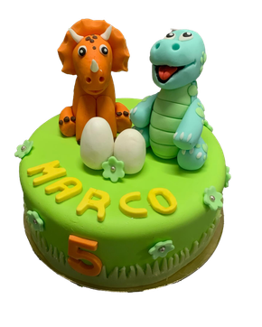 Un gâteau d'anniversaire vert décoré de deux figurines de dinosaures, de deux œufs blancs, de petites fleurs, du nom MARCO et du chiffre 5.