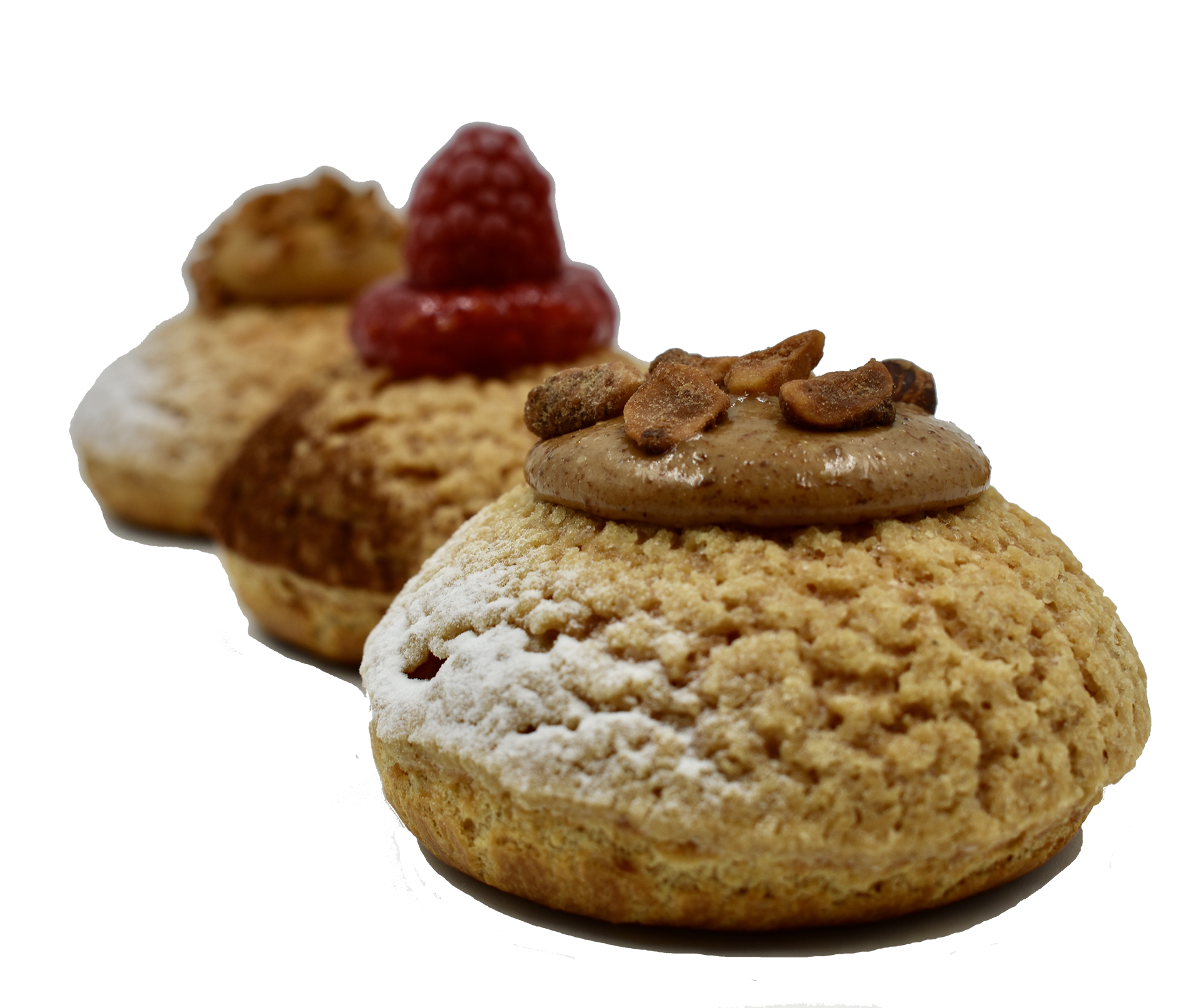 Trois choux à la crème alignés en diagonale, garnis de crème au chocolat, d'une framboise fraîche et de noix grillées, saupoudrés de sucre.
