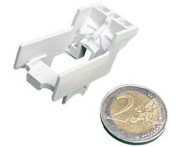 Pièce en plastique blanc placée à côté d'une pièce de deux euros pour comparaison d'échelle.