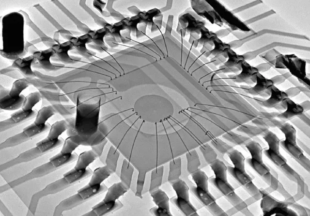 Vue radiographique d'une carte de circuit imprimé avec une puce centrale reliée par de fins fils.