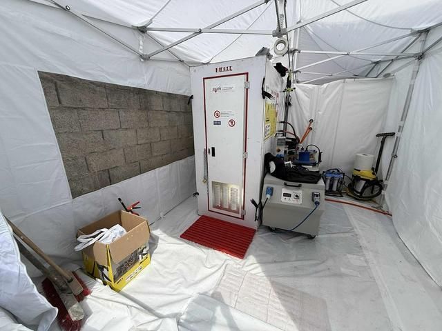 À l'intérieur d'une tente blanche, une chambre de décontamination est installée sur un tapis rouge.