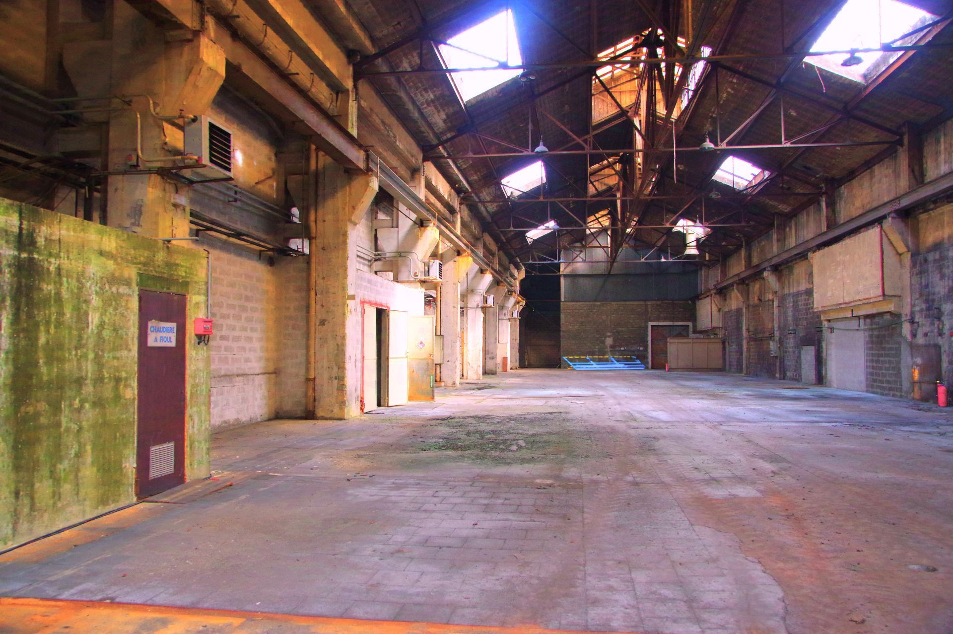 Intérieur d'un grand bâtiment industriel abandonné. Sol en béton, murs en briques et poutres en acier. 
