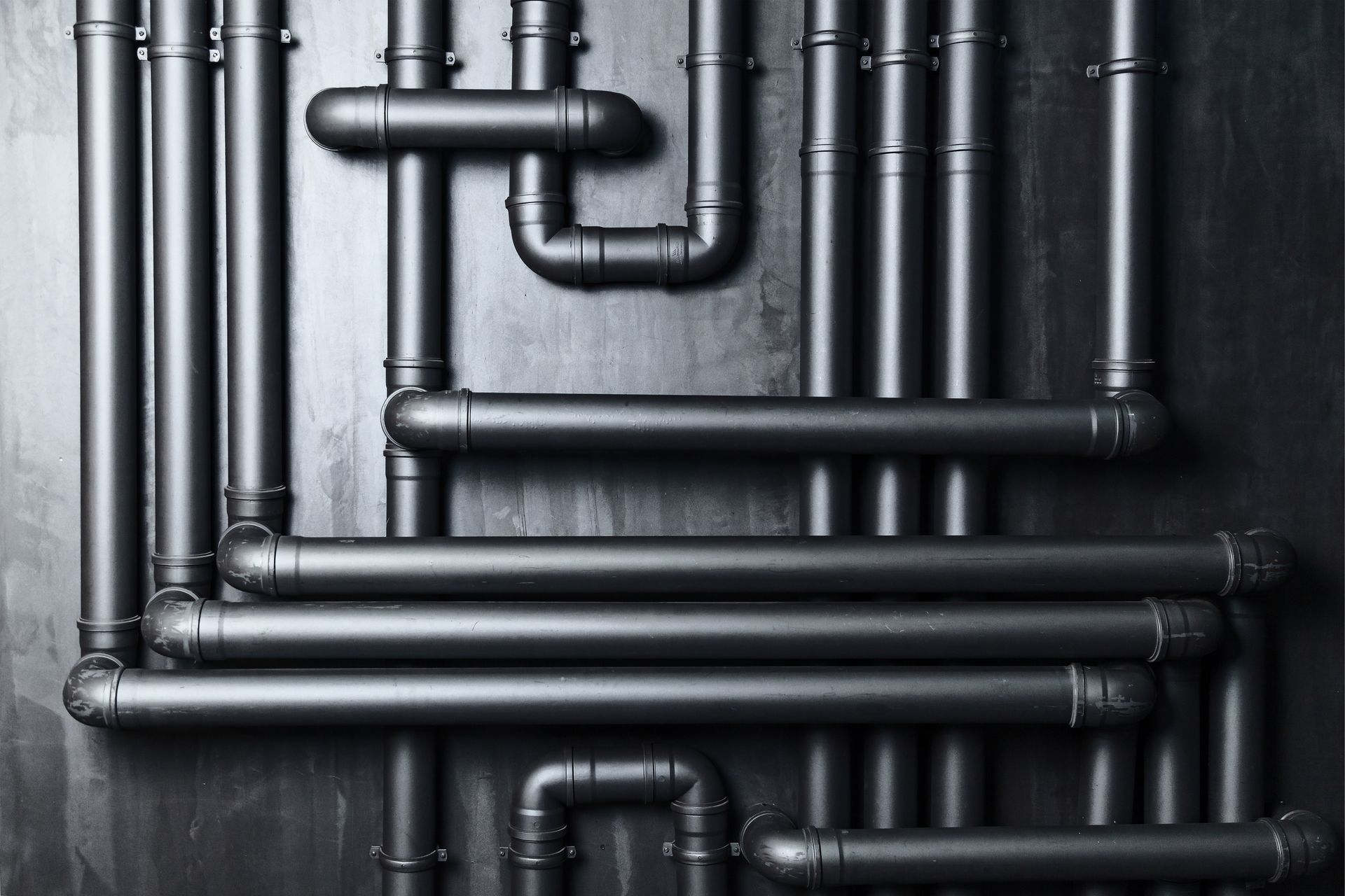 Tuyaux noirs contre un mur sombre, design industriel.