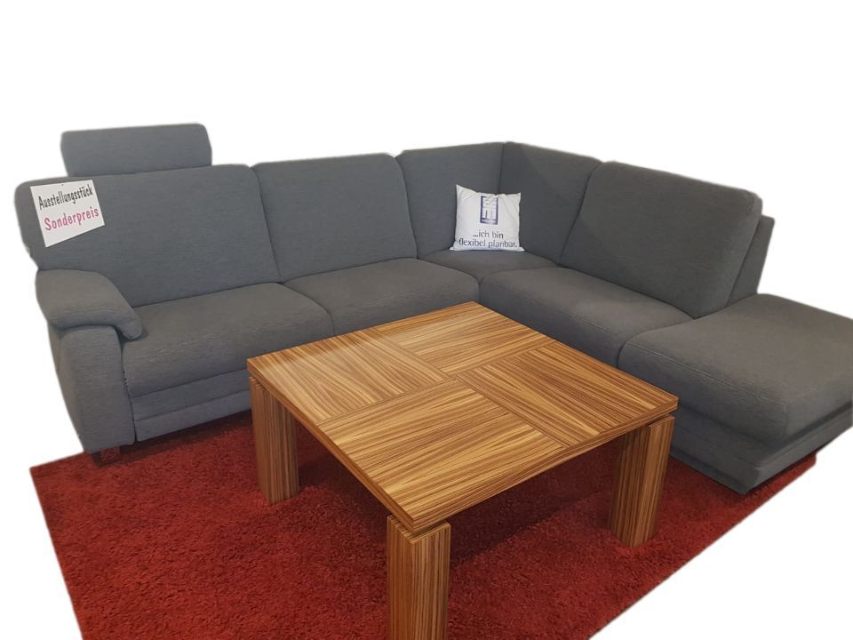L-förmiges Sofa mit Kopfstütze hinter einem Holz-Couchtisch
