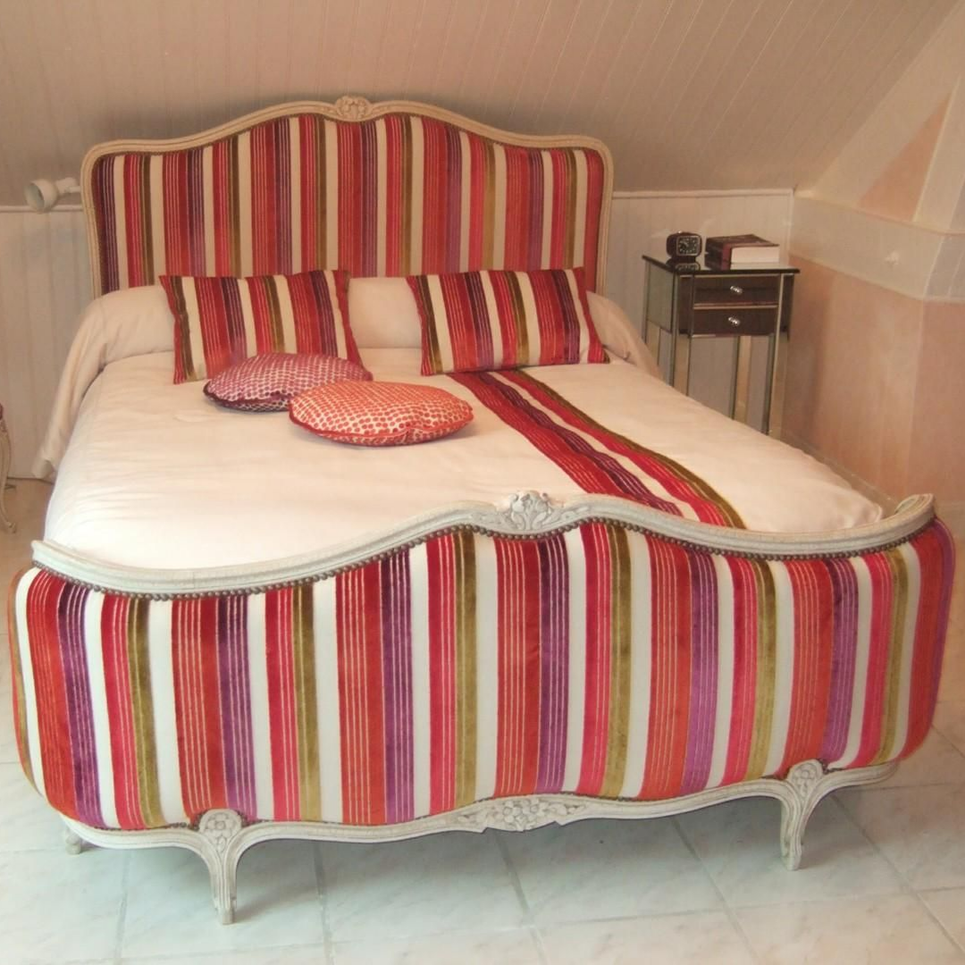 Lit avec tête de lit à motifs, tables de chevet et chemin de lit fleuri.