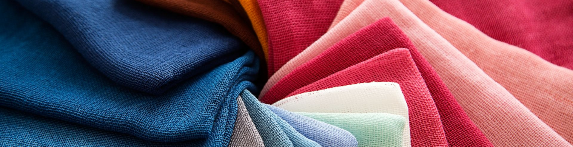 Tissus colorés dans les tons de bleu, de rouge et de rose, disposés en couches.