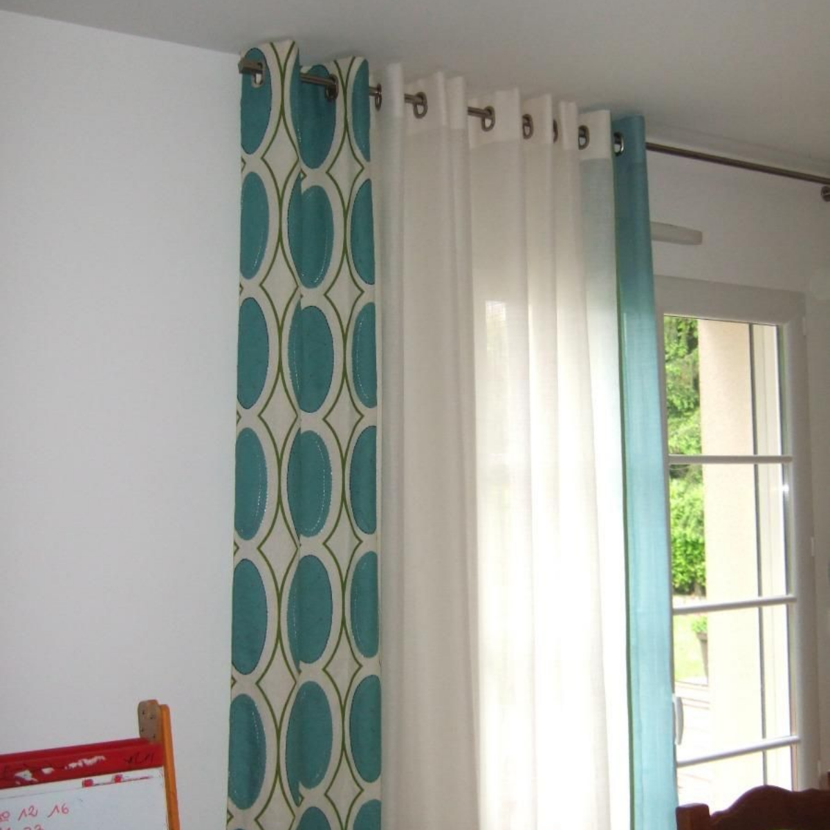 Rideaux : un à motifs turquoise, un voilage blanc et un uni turquoise.