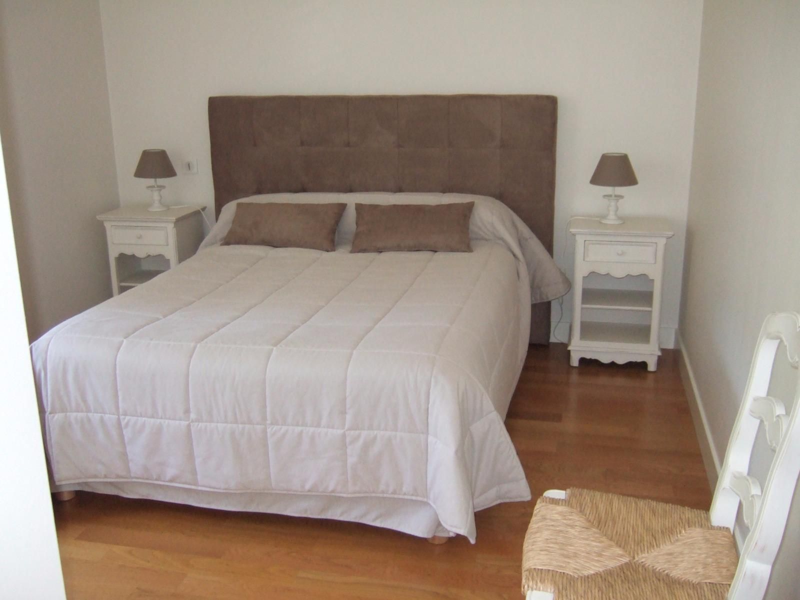 Chambre avec lit, tables de chevet, lampes et chaise.