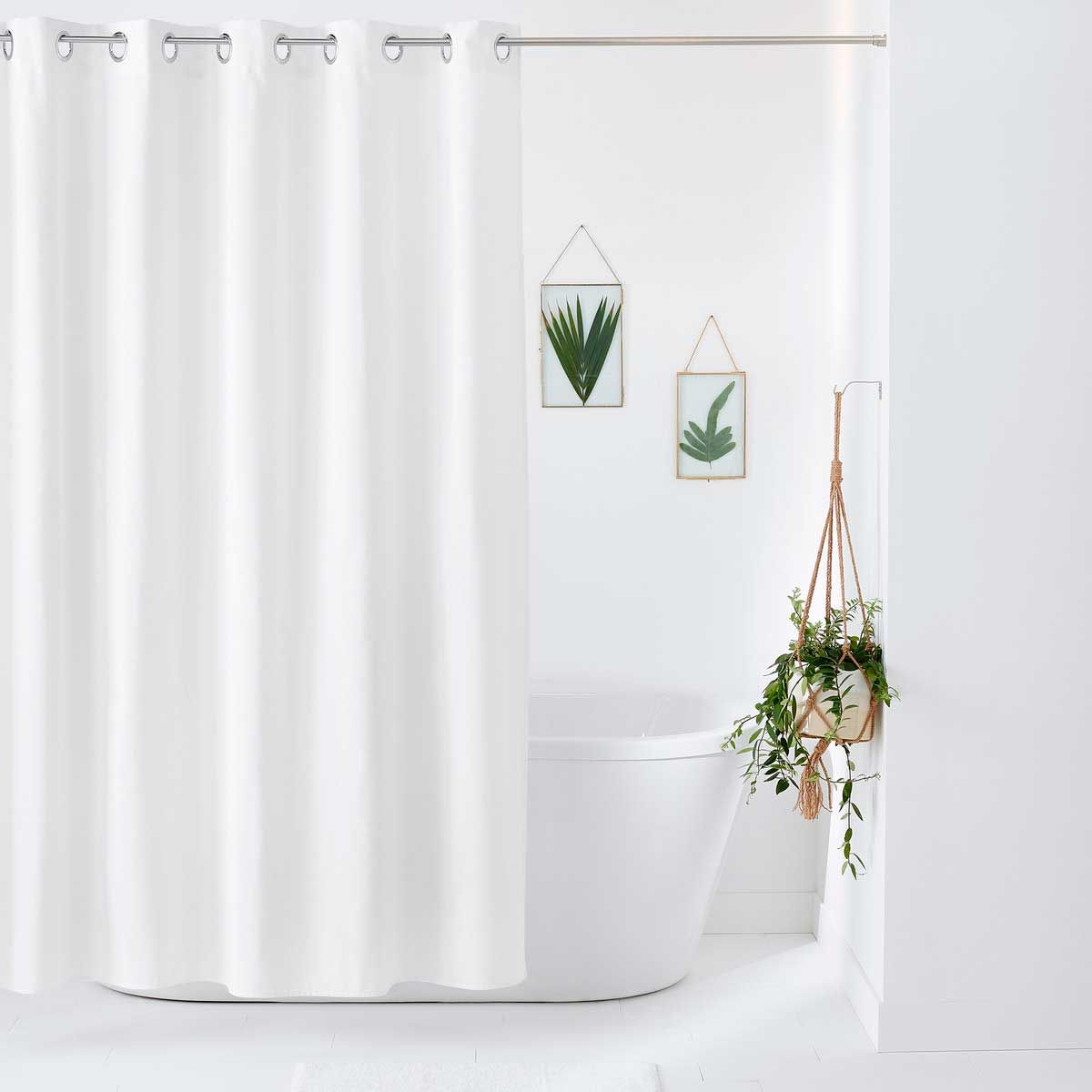 Una cortina de ducha blanca cuelga sobre una bañera en un baño.