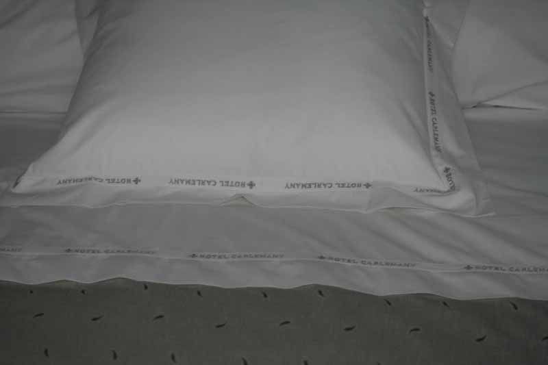 Una almohada blanca está sobre una cama con sábanas blancas.