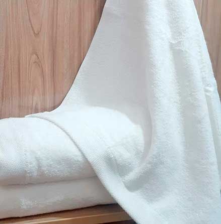 Una pila de toallas blancas colocadas una encima de otra en un estante de madera.