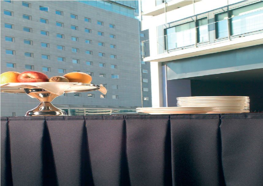 Un bol de fruta reposa sobre una mesa frente a un edificio.